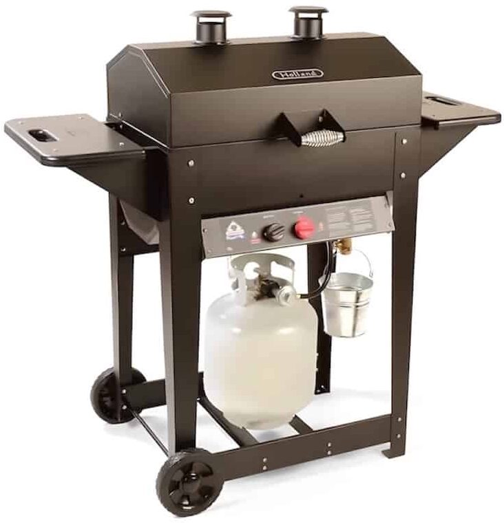 Black propane gas grill featuring two chimneys, side shelves, a propane tank stored beneath, two wheels on one side for mobility, and a grease bucket attached below the control panel. The grill is set against a white background.